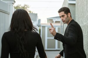 Man threatening his partner. Lowering self-esteem and controlling your autonomy are signs of coercive control.